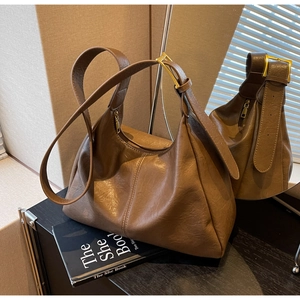 Detail of a brown leather Hobo bag with gold buckles and premium textured finish