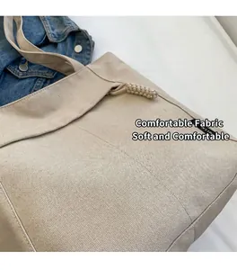 Detalle del bolso tote de lona beige con cordón trenzado y etiqueta de marca tejida