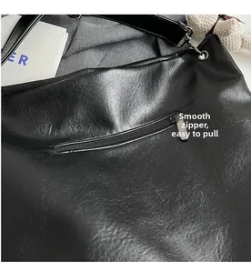 Detail of smooth silver zipper on black textured leather tote bag with pocket