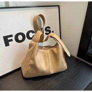 Detail view of beige tote bag with textured faux leather and adjustable gold buckle