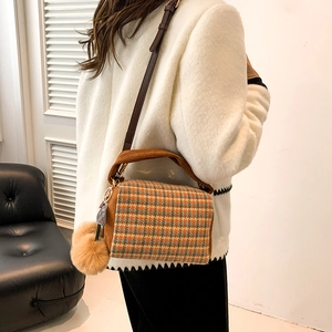 Classic orange-brown houndstooth Boston bag with plush ball charm and leather strap