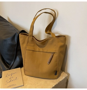 Detalle del bolso tote de lona amarillo jengibre con tirador trenzado sobre piedra