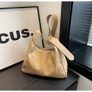 Detail of beige hobo bag showing lychee grain faux leather and adjustable wide strap