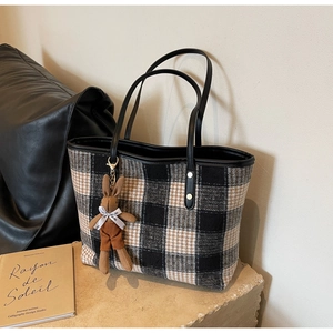 Detail of classic plaid tote bag with faux leather handles and a plush rabbit pendant