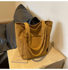 Primer plano de la textura de lona amarilla y el bolsillo frontal de este bolso de mano