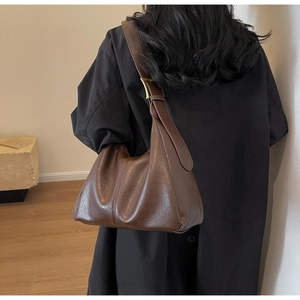Detailed view of the large brown leather tote bag showing a wide strap and glossy texture