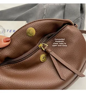 Detail of brown lychee leather crossbody bag featuring invisible magnetic snaps and zipper