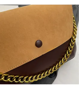 Close-up of contrast stitching on two-tone suede and leather handbag with gold chain