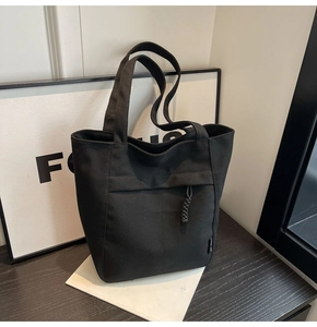 Primer plano de un bolso tote de lona negra sobre una mesa con detalles de tejido