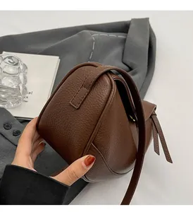 Detail of dark brown pebble leather crossbody bag with tassel and adjustable strap
