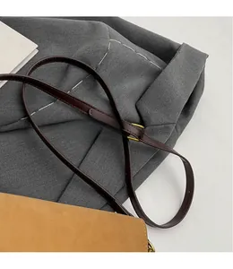 Detail of adjustable dark brown leather shoulder strap with golden metal buckle on handbag