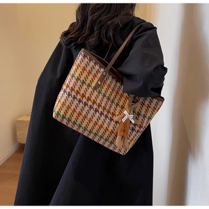 Detail of colorful houndstooth tote bag with leather straps and a plush bear pendant