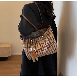 Detail of colorful houndstooth tweed tote bag with leather strap and rabbit charm