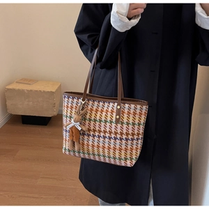 Detail of tweed checkered tote bag with brown leather handles and plush bunny charm