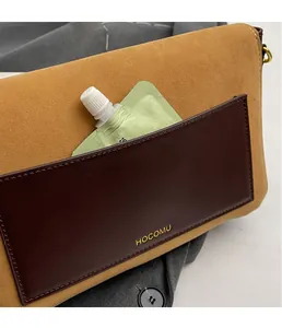 Detail shot of vintage suede shoulder bag with front leather pocket and gold logo