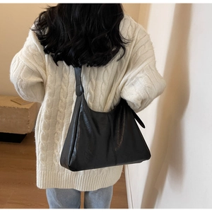 Detail of black leather tote bag worn by model showing daily shoulder carry capacity