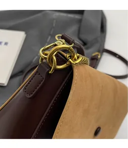 Close-up of golden ring hardware and texture of brown leather crossbody bag