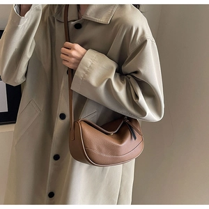 Close-up of brown pebbled leather texture and black zipper detail on the crossbody bag
