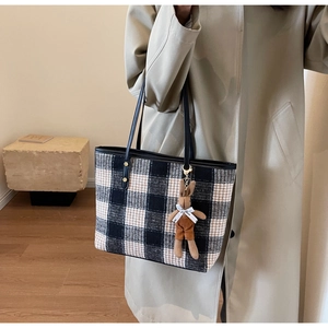 Close-up of black and white checkered tote bag with a cute bunny charm and leather strap