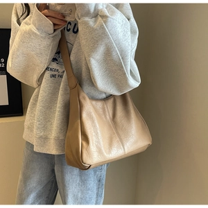 Detail of beige large tote bag in textured PU leather showing shoulder strap and stitching
