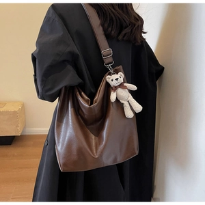 Brown leather tote bag showing Hobo style draping and a cute bear keychain detail
