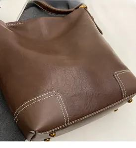 Gros plan du fond du sac seau en cuir marron foncé avec surpiqûres et pieds en laiton