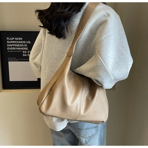 Detail of beige hobo bag showing wrinkled leather texture and wide shoulder strap