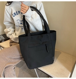 Primer plano de bolso tote de lona negra con etiqueta tejida y costuras detalladas