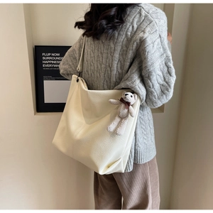 Detail of a large beige tote bag in soft PU leather with a cute teddy bear charm