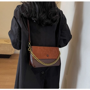 Detail of vintage crossbody bag with gold chain and suede texture on black coat
