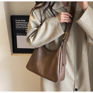 Detail of vintage brown leather tote bag with wide strap and gold hardware on model