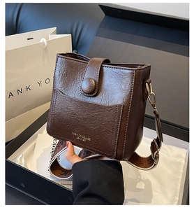 Close-up of retro brown leather bucket bag with wide strap and gold hardware details