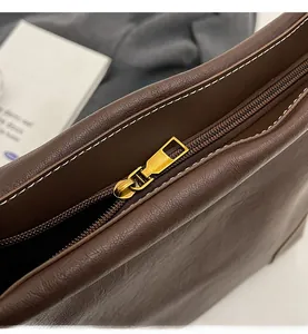 Détails du zip fluide et des surpiqûres blanches sur ce sac seau en cuir marron foncé