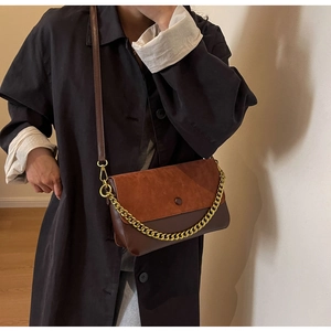 Detail of vintage brown shoulder bag with golden chain and adjustable leather strap