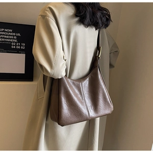 Brown retro crescent bag detail showing pebbled leather texture and gold buckle adjustment