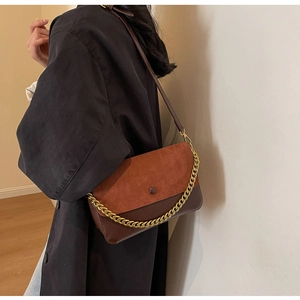 Detail of the vintage-style chain crossbody bag featuring dark brown leather and red suede