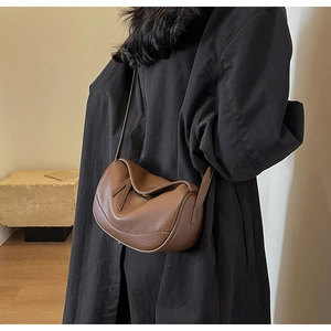 Detail of a brown lychee pattern leather crossbody bag with metal twist-lock and shoulder strap