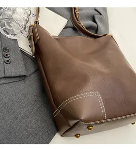 Détails du sac seau marron foncé avec coutures contrastées blanches et pieds de protection