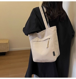 Detalle de bolso tote de lona blanco roto con bolsillo exterior y nudo tejido
