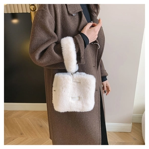 Detail einer weißen flauschigen Eimertasche mit Plüschgriff und dekorativem Etikett