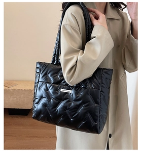 Detail of black quilted tote bag with white fashion tag and soft padded texture