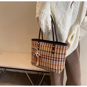 Detail of houndstooth tote bag with brown leather strap and cute rabbit pendant charm