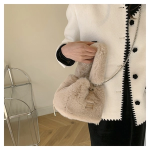 Detail der weichen Plüsch-Beuteltasche in Beige mit silberner Kette und Tragegriff