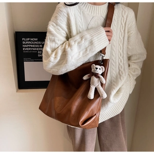 Detailed close-up of brown faux leather tote bag with a cute white teddy bear charm