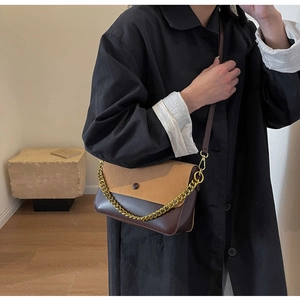 Detail of a brown patchwork crossbody bag featuring gold chain and retro round buckle