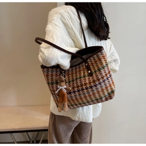 Detail of multi-colored woven tote bag with brown leather strap and cute bunny charm