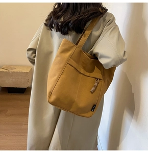 Detalle del bolso tote de lona amarillo jengibre con bolsillo y etiqueta de marca