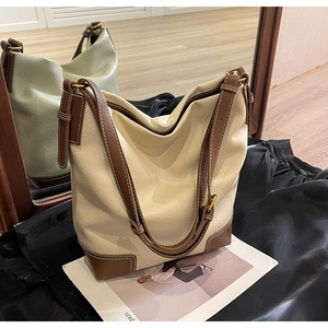 Détail du grand sac seau crème avec bordure marron et coutures de précision