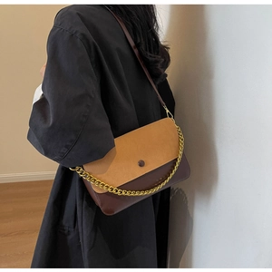 Detail view of the retro two-tone crossbody bag with gold chain strap on a model