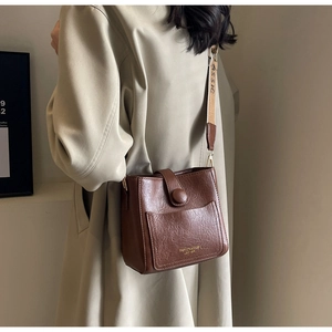 Gros plan détaillé du sac seau vintage marron en similicuir texturé avec large bandoulière